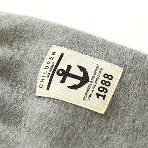 Close-up of children's grey knit trousers featuring a vintage anchor patch and 1988 print