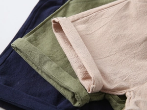 Detail view of cotton linen fabric textures in navy, olive, and beige with neat stitching