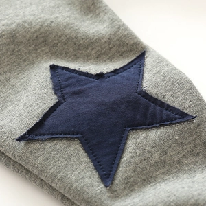 Gray knitted fleece pants for boys with navy blue star patch and raw edge detail
