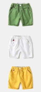 Detailed view of kids cotton shorts in green, white and yellow with elastic waist