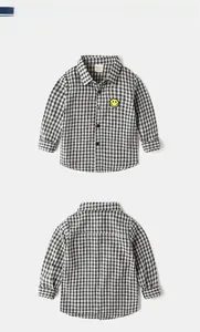 Detailed view of kids cotton long sleeve shirt with black white grid and yellow smiley patch
