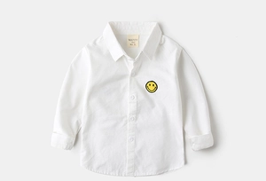Close-up of white long sleeve toddler shirt with a yellow smiley face patch on the chest