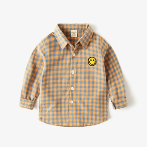 Detail shot of blue and orange checkered shirt with yellow smiley face patch on chest
