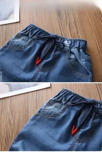 Dettaglio dei pantaloncini di denim blu da bambino con vita elastica e stampa di auto