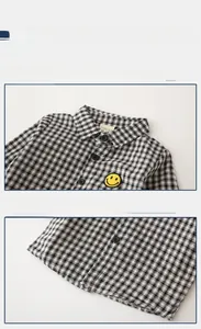 Close-up of black and white checkered kids shirt with yellow smiley face patch detail