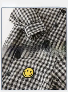 Close-up of black and white checkered kids shirt with yellow smiley embroidery
