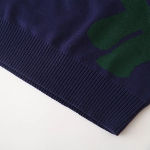 Primer plano del tejido de punto azul marino con patrón verde y dobladillo acanalado