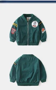 Close-up of green bomber jacket detailing vintage embroidery patches and ribbed collar