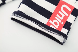 Detail of navy blue and white striped cotton shorts with red Unique graphic patch
