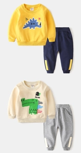 Détail d'ensembles deux pièces pour garçon avec motifs dinosaures en jaune et blanc