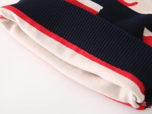 Detail of navy ribbed cuff and red stripe on cream knit boy's sweater sleeve