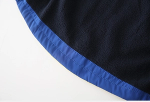 Dettaglio in pile nero con bordo in nylon blu e rifinitura con cuciture a doppio ago