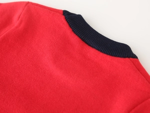 Detail of red knit sweater featuring a navy blue ribbed crewneck and soft cotton texture