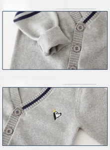 Detail of grey knitted cardigan with navy stripe cuffs and crown penguin embroidery