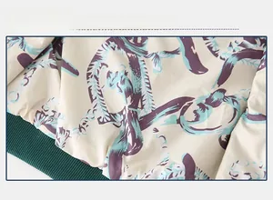 Close-up of boys' baseball jacket fabric featuring teal and purple dragon patterns