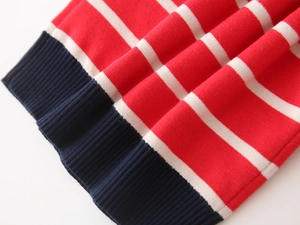 Macro detail of red and white striped knit fabric with dark blue ribbed cuff