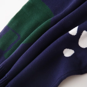 Detalle del tejido de punto en azul marino y verde con diseño de lunares blancos