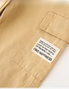 Detail of khaki cargo pants featuring a side flap pocket with a white textile patch