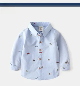 Detail of light blue Oxford shirt for boys with cartoon prints and brown wood buttons