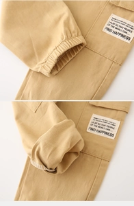 Detail of khaki cargo pants featuring elastic cuffs and white Find Happiness fabric label