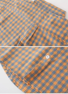 Details der Nähte am Kragen und Knopfsaum des orangefarbenen Kinder-Karohemds