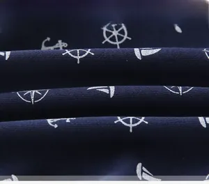 Close-up of navy blue cotton knit fabric with white nautical anchor and sailboat print