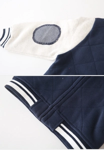 Detail of boys baseball jacket featuring diamond quilted fabric and striped ribbed cuffs