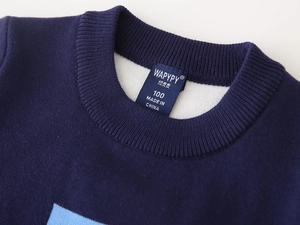 Close-up of ribbed crew neck and brand label on navy blue knitted sweater for boys