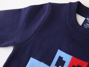Detail of navy knit sweater with ribbed neckline and geometric car pattern stitching