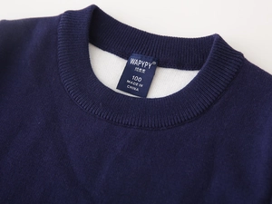 Macro view of navy blue knit sweater neckline with ribbed collar and woven label detail