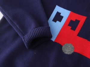 Close-up of boys knit sweater featuring a colorful bus pattern and ribbed cuffs detail