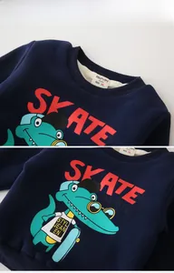 Detail of navy fleece sweatshirt featuring a cartoon crocodile print and SKATE lettering
