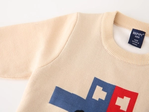 Close-up of knit sweater neckline with woven size label and blue car pattern detail