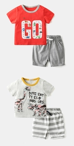 Detail view of two sets of boys' cotton short sleeve t-shirts and shorts with dinosaur prints