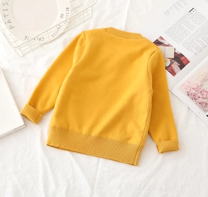 Detailed view of ginger yellow kids sweater with ribbed crew neck and soft knit texture