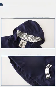 Detail of kids hooded windbreaker with red zipper and striped lining on navy fabric