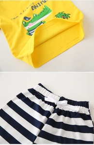 Detail of cotton kids summer set showing yellow T-shirt with crocodile print and striped shorts