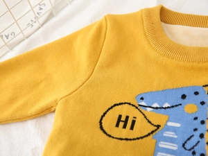 Detail of yellow knit sweater with blue cartoon crocodile and warm fleece lining