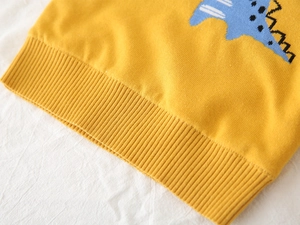 Detail of yellow knit sweater featuring blue dinosaur pattern and ribbed hem for kids