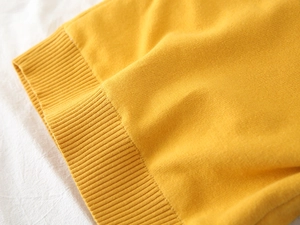 Close-up of ginger yellow knit sweater showing detailed ribbed cuffs and soft texture