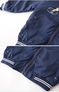 Detail of navy blue kids jacket showing striped cuffs and dog cartoon embroidery