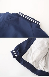 Detail of dark blue windbreaker neck and hem with white striped ribbing and soft gray lining