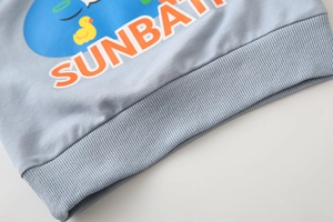 Detail view of light blue children's sweatshirt with ribbed hem and SUNBATH print