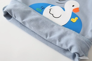 Close-up of baby sweatshirt light blue knit fabric with cute cartoon white duck prints