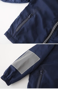 Détail d'un coupe-vent bleu marine avec bande réfléchissante et poche zippée