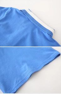 Détail d'un polo bleu montrant le col rayé et les coutures de haute qualité du tissu