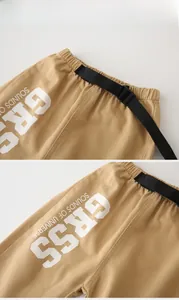 Close-up of kids khaki trousers featuring adjustable belt and white letter printing