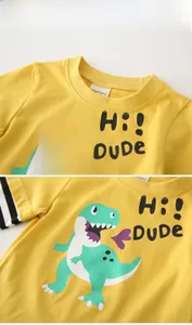 Detail of yellow kids t-shirt with cartoon dinosaur print and striped patchwork sleeves