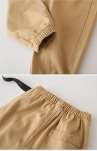 Detail of khaki kids' trousers showing elastic waistband, pocket and cuffed hem