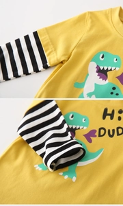 Detail of yellow kids long sleeve shirt showing dinosaur print and striped cuffs